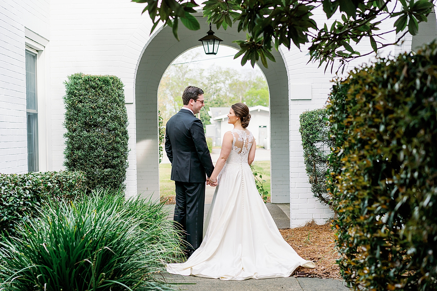 Bride and groom holding hands under and archway | Photo by Annie Laura Photography