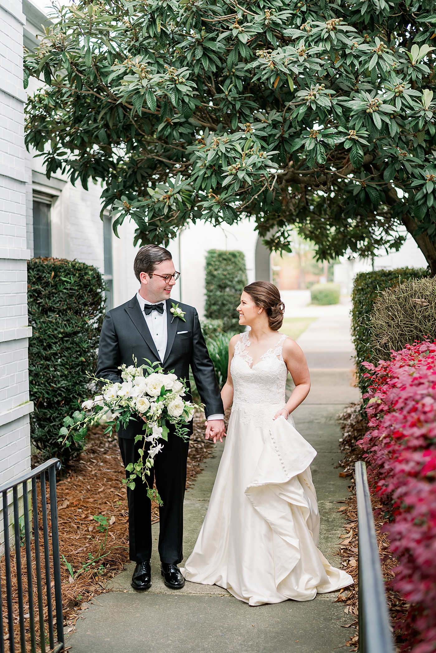 Bride and groom walking together on a sidewalk near a church | Photo by Annie Laura Photography