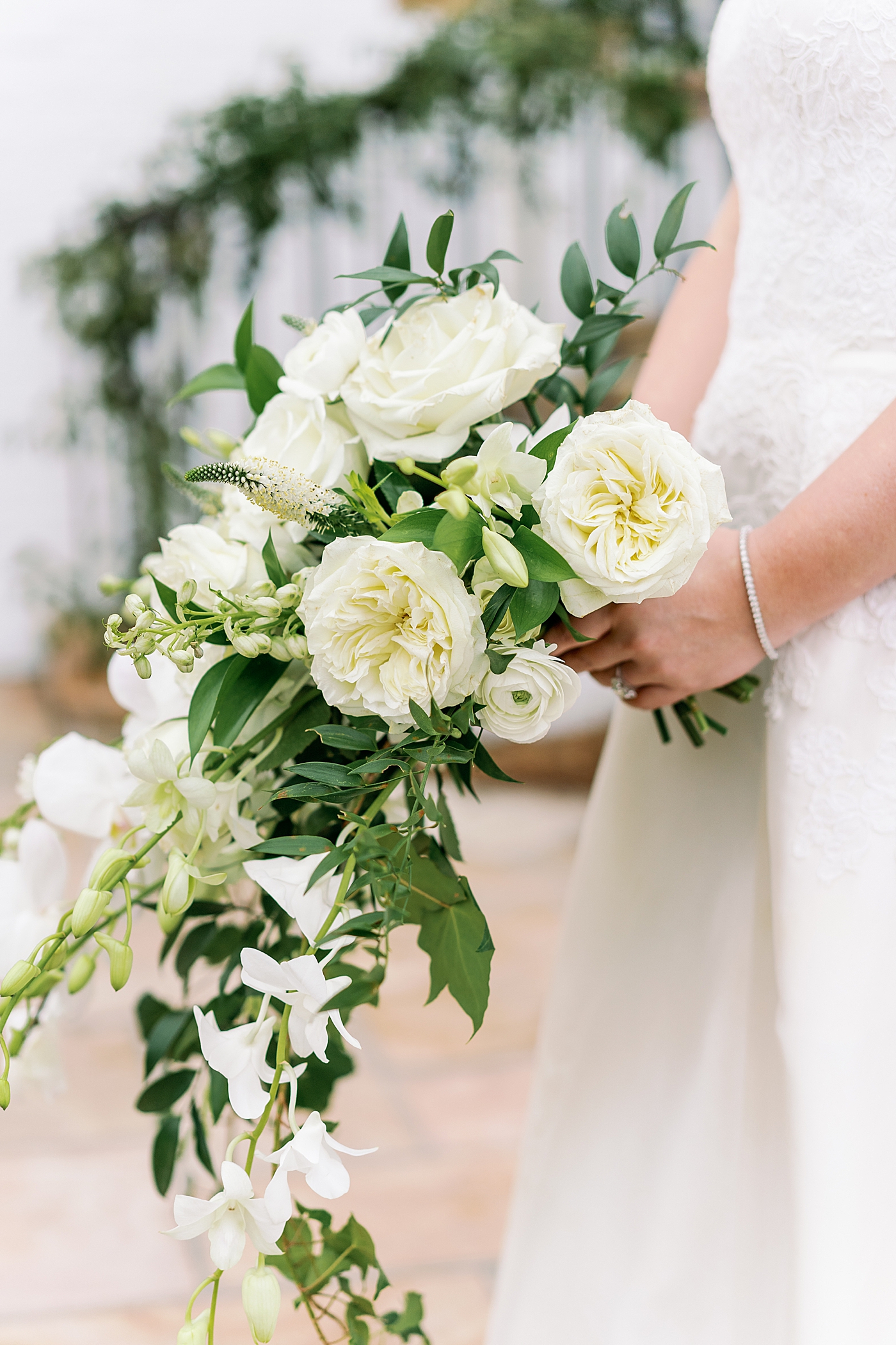 Bride holding her bouquet with white roses and orchids | Photo by Annie Laura Photography