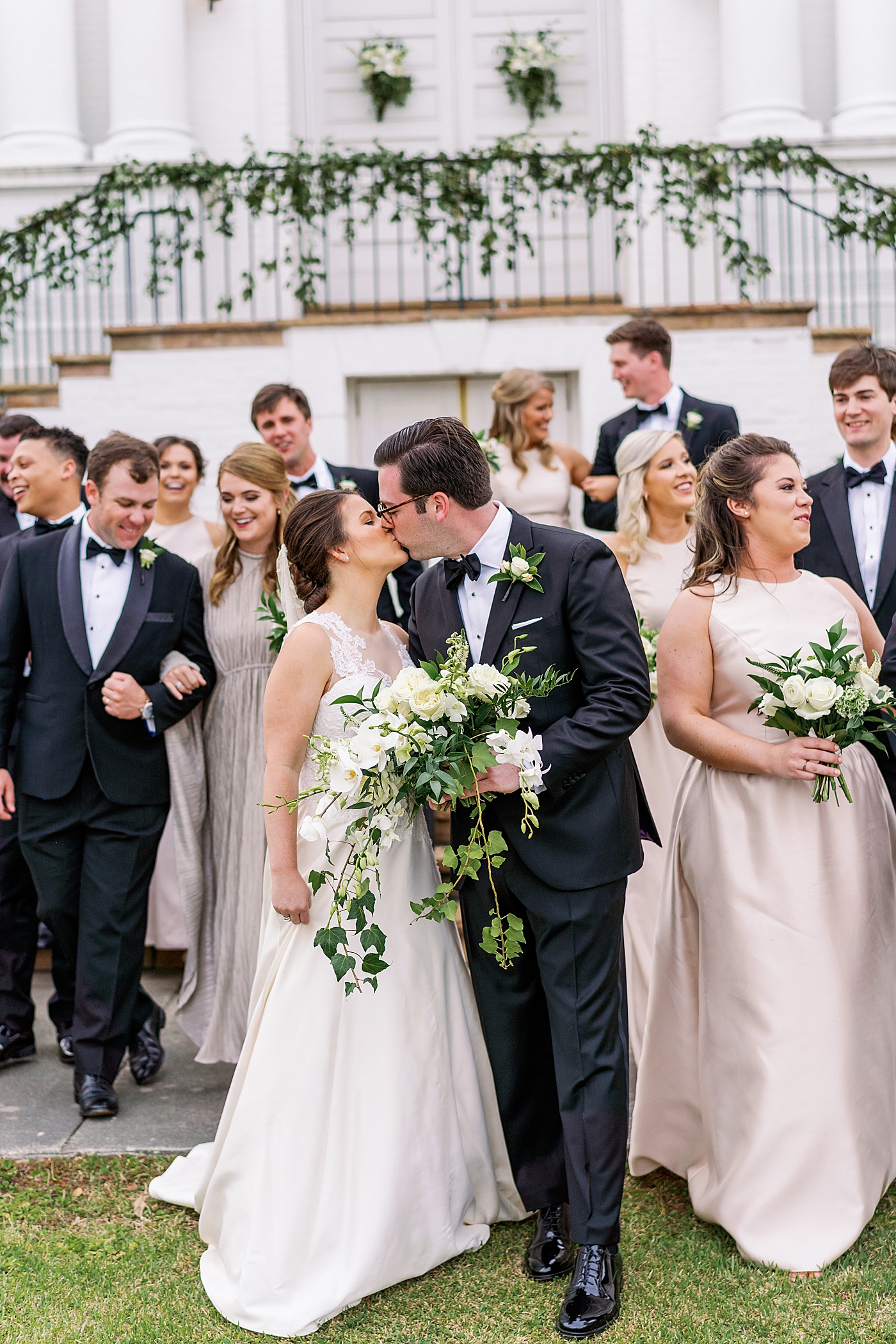 Bride and groom kissing standing in front of their wedding party | Photo by Annie Laura Photography