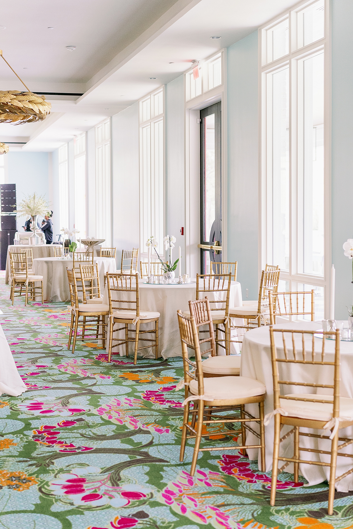 Colorful rug under gold chairs and tables with cream tablecloths | Photo by Annie Laura Photography