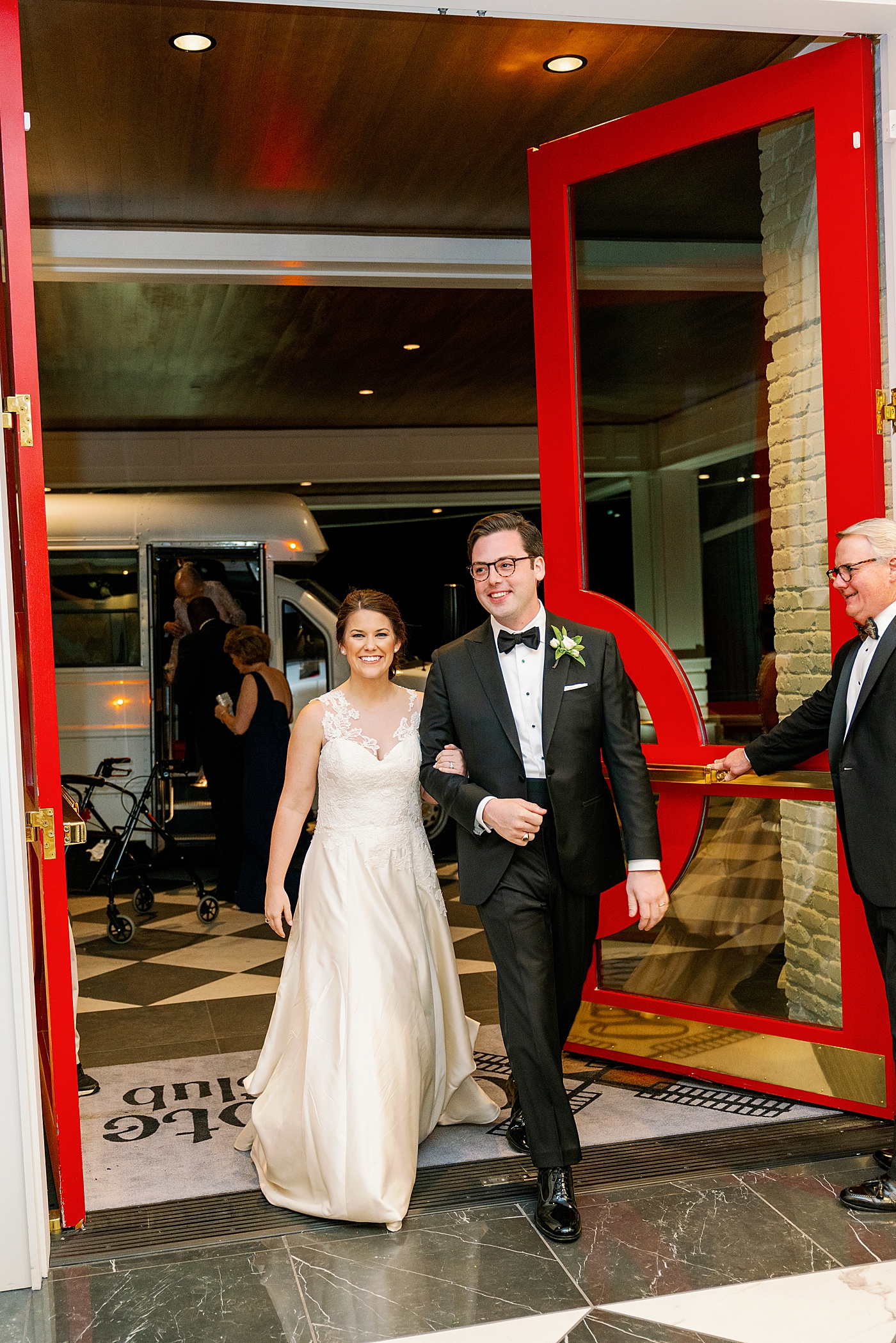 Bride and groom leaving their reception through bright red doors | Photo by Annie Laura Photography