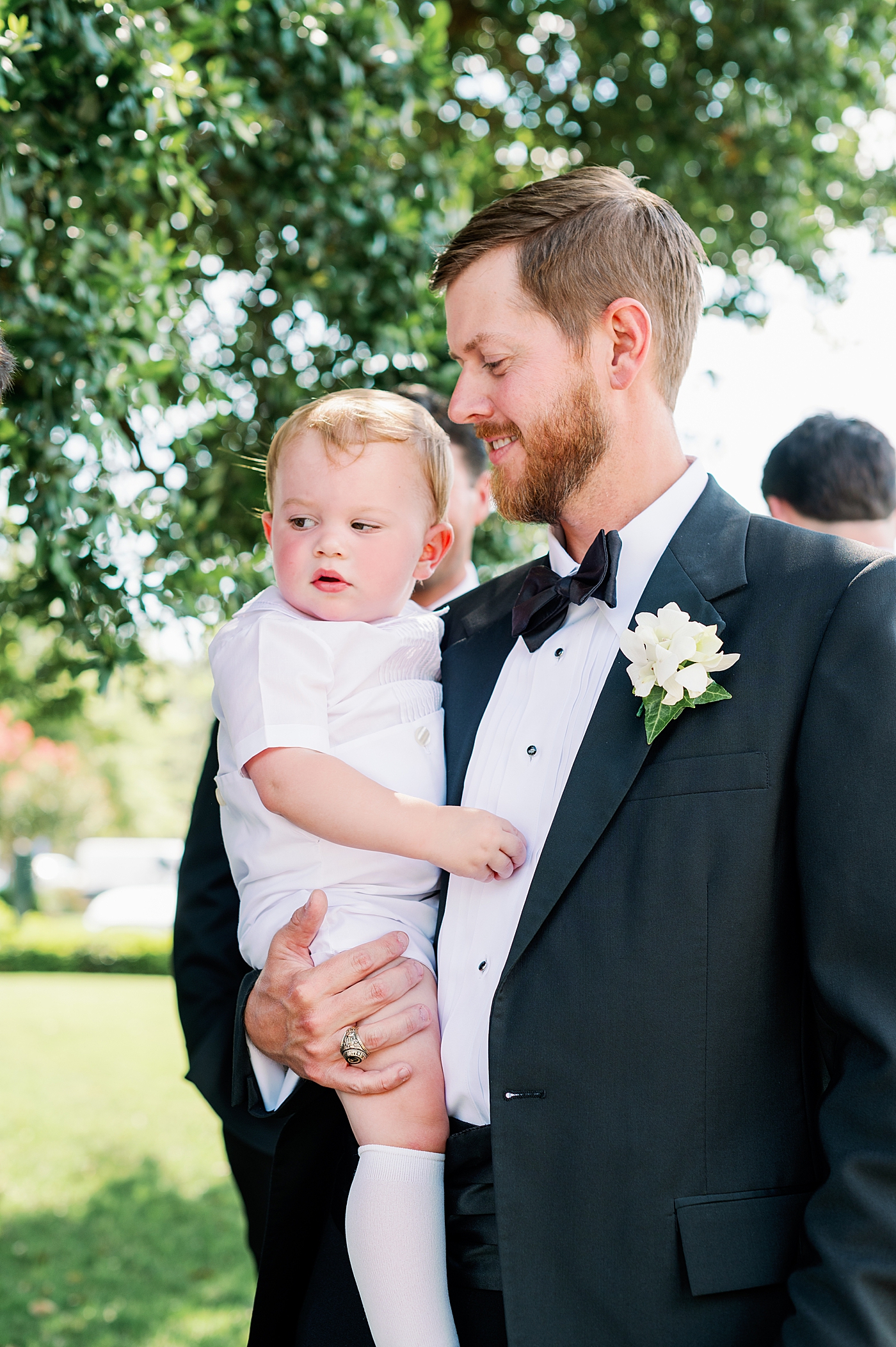 Groomsmen holding baby in white outfit | Image by Annie Laura Photo