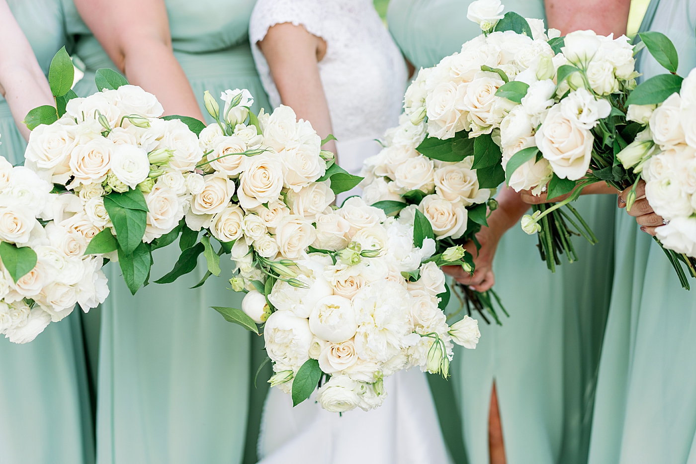Bridesmaids in green dresses holding their wedding flowers | Image by Annie Laura Photo