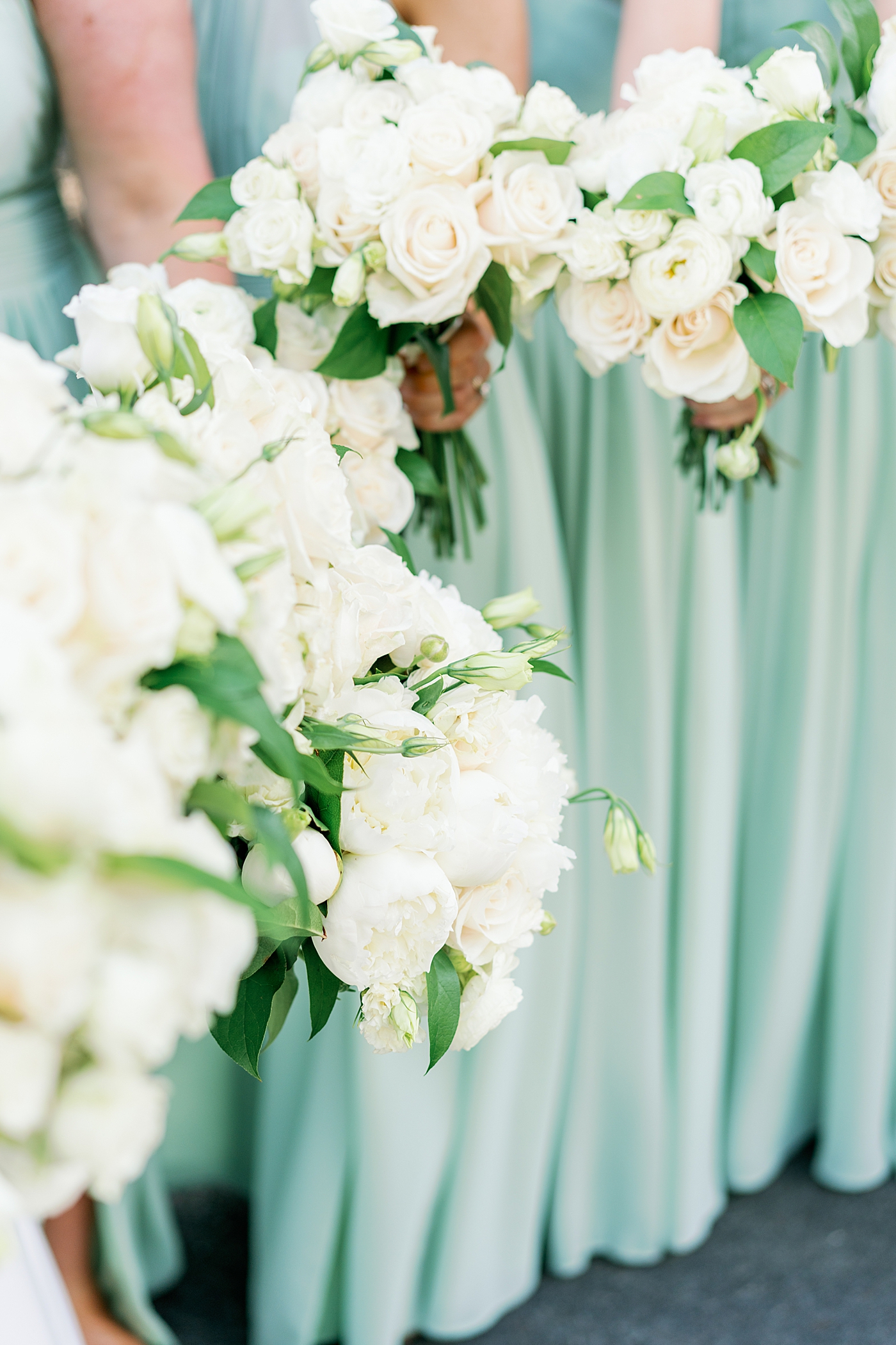 Bridesmaids bouquets with green dresses in the background | Image by Annie Laura Photo
