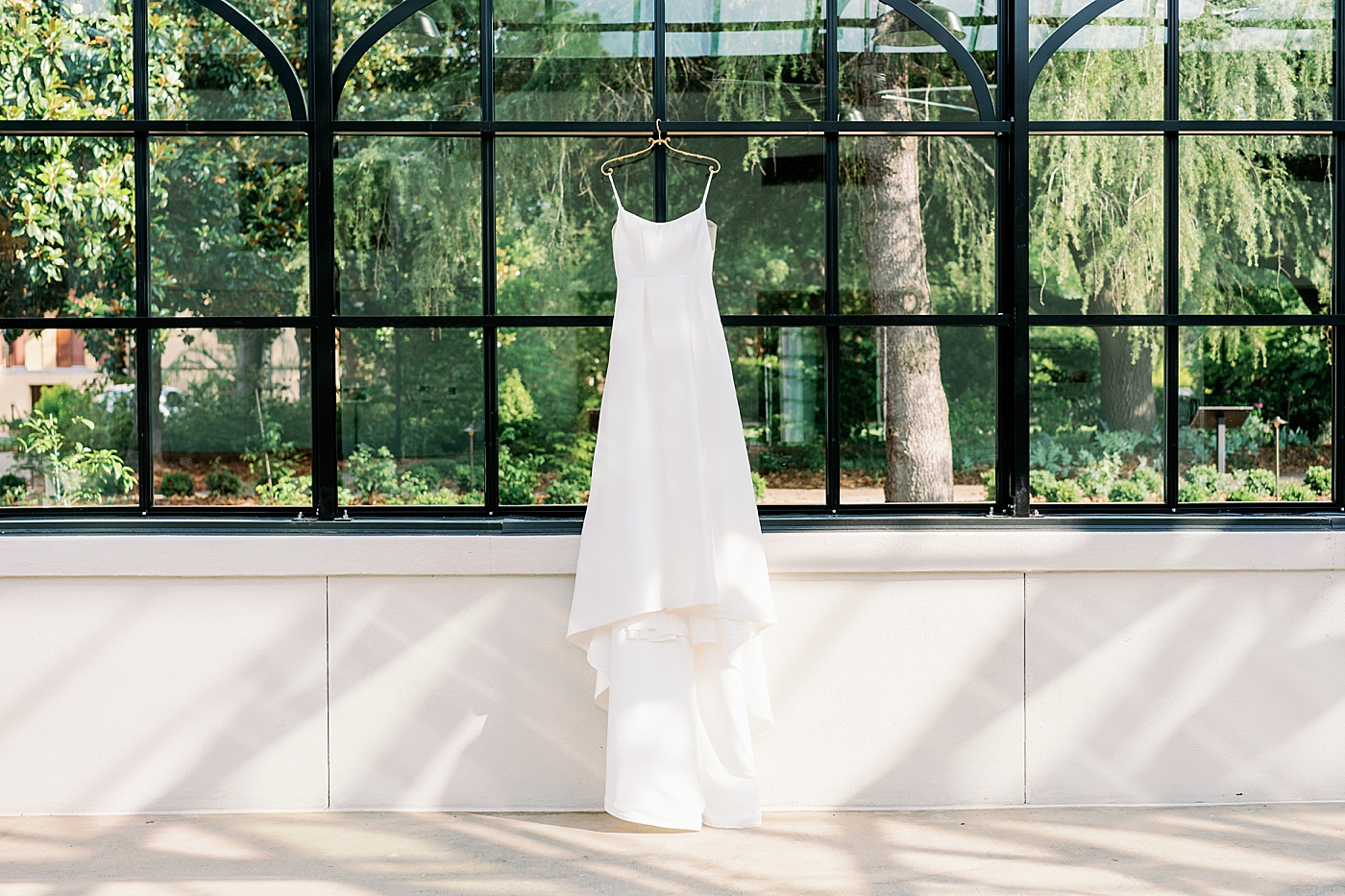 Bridal gown hanging in a greenhouse for summer inspired garden wedding | Photo by Annie Laura Photo