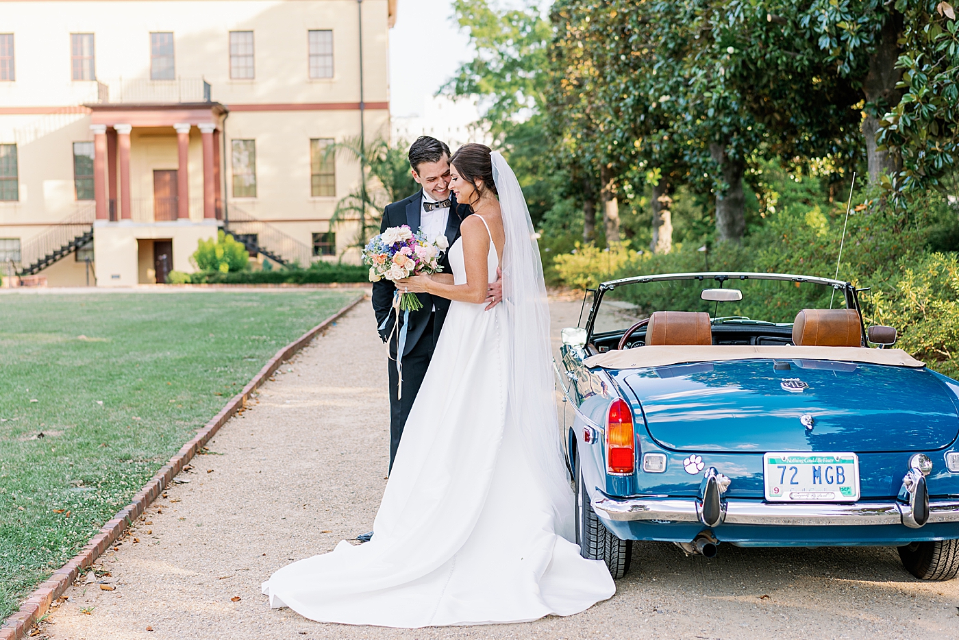 Bride and groom posing by blue vintage car | Photo by Annie Laura Photo