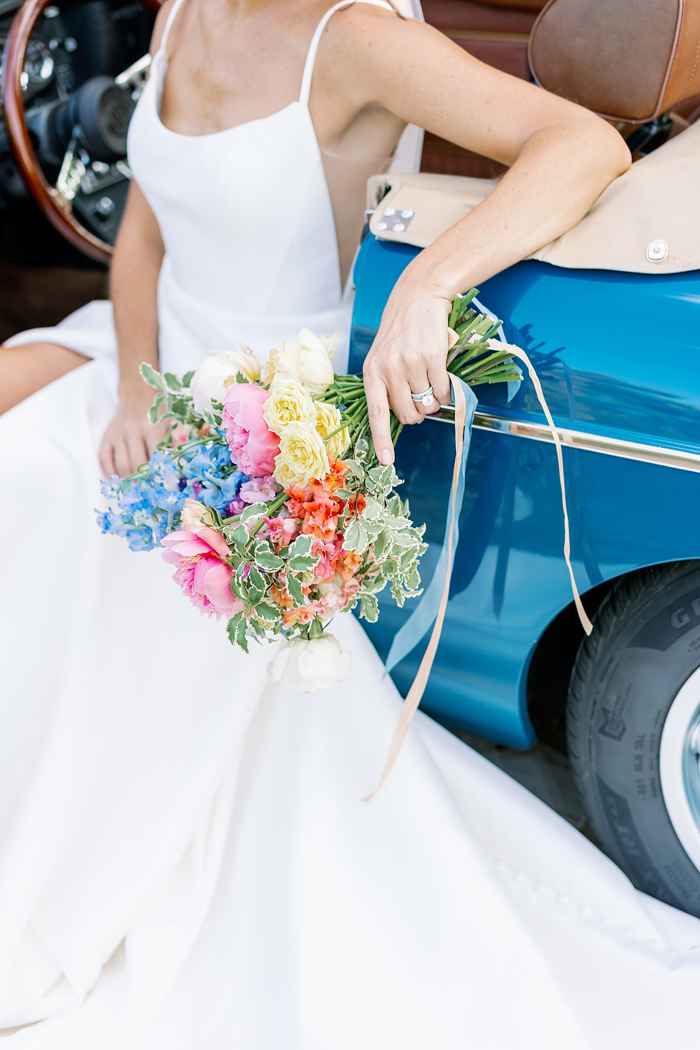 Bride sitting in a blue antique car holding her bouquet | Photo by Annie Laura Photo
