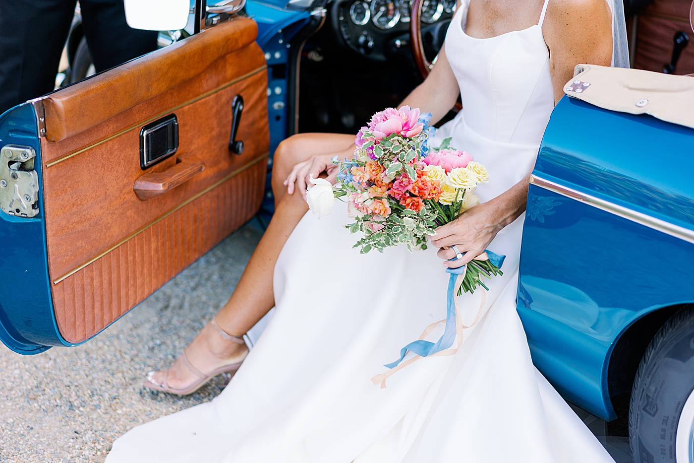 Bride sitting in a blue vintage car holding her bouquet | Photo by Annie Laura Photo