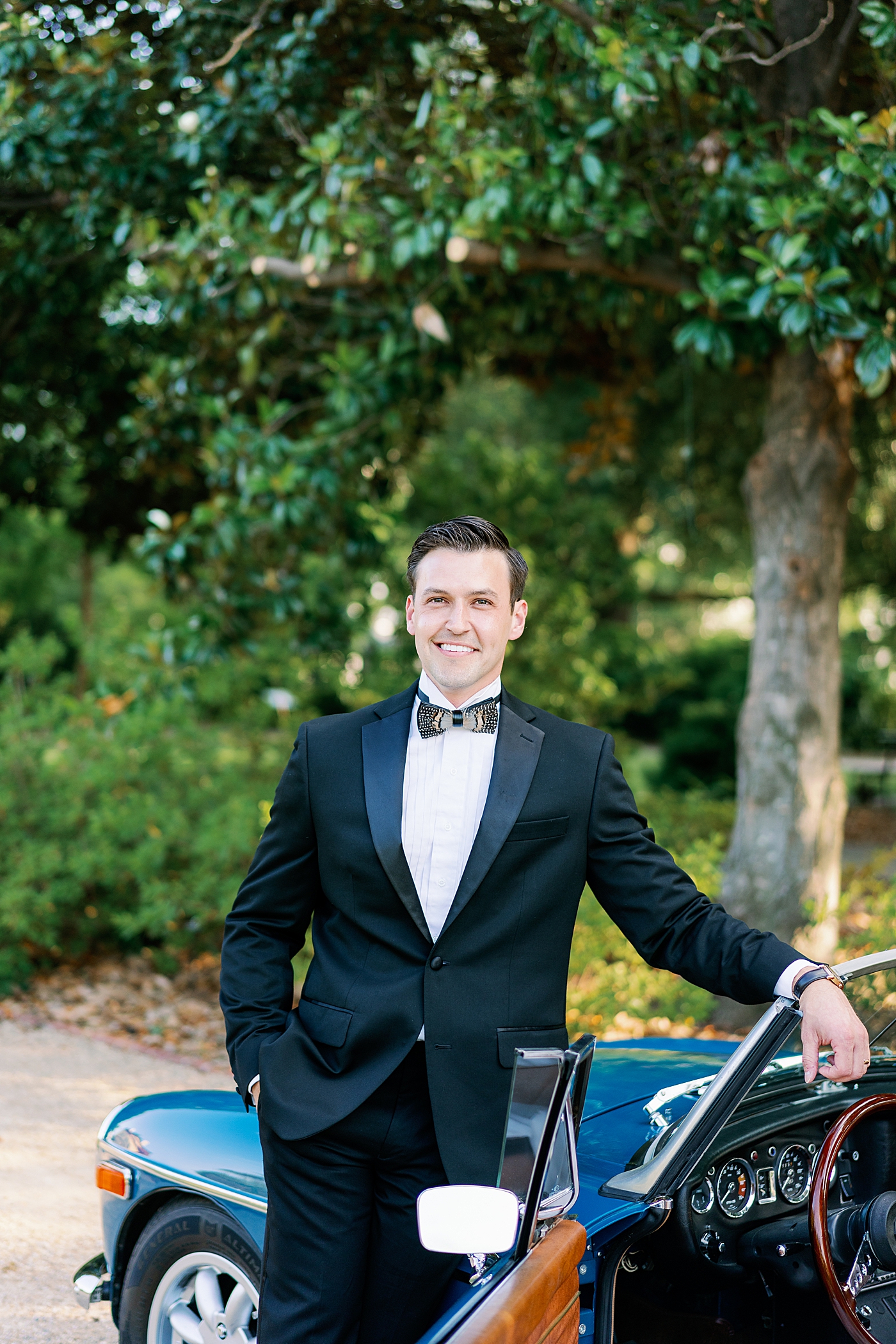 Groom standing by blue antique car at Boyd Foundation Horticultural Center | Photo by Annie Laura Photo
