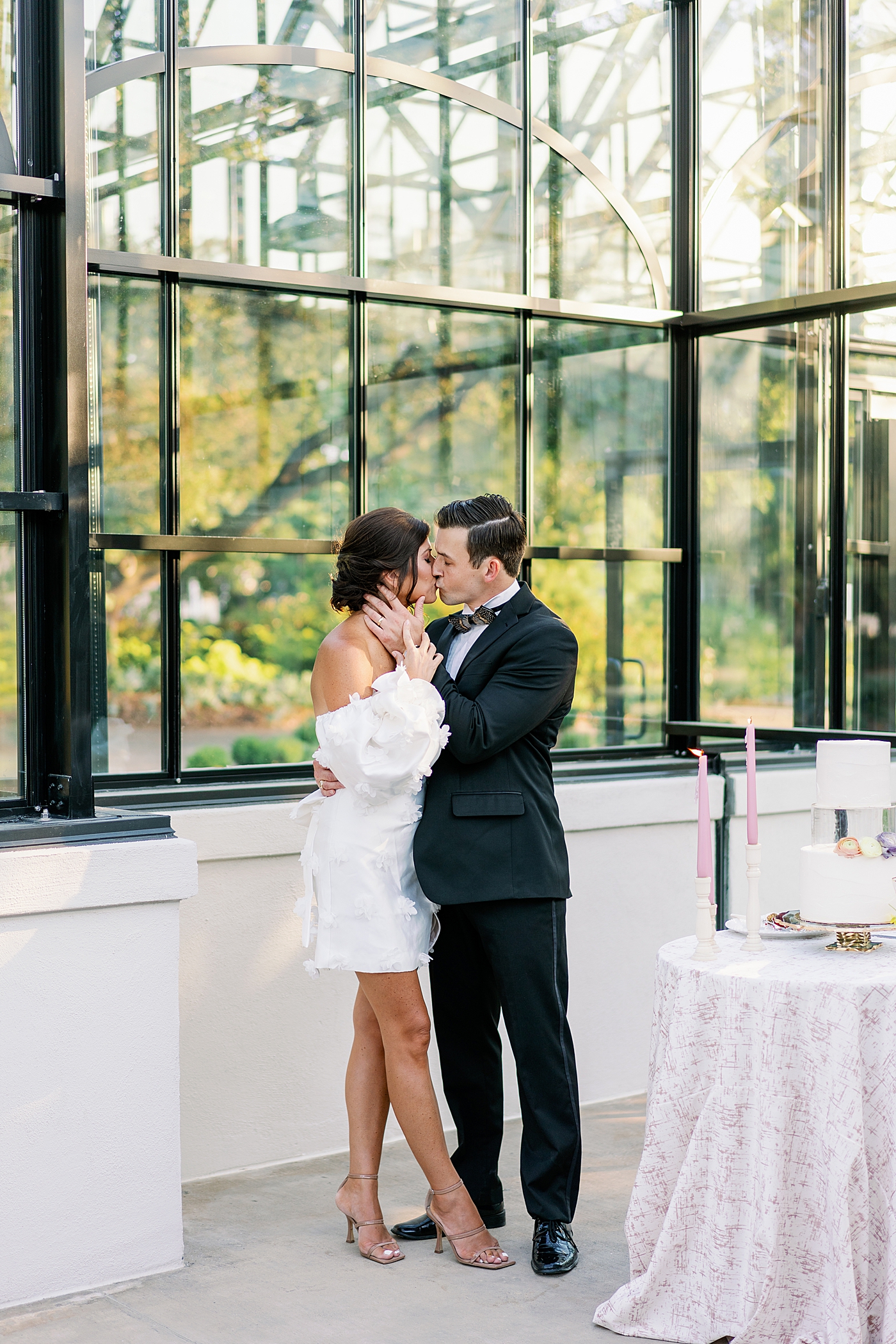 Bride and groom kissing by cake table during summer inspired garden wedding | Photo by Annie Laura Photo