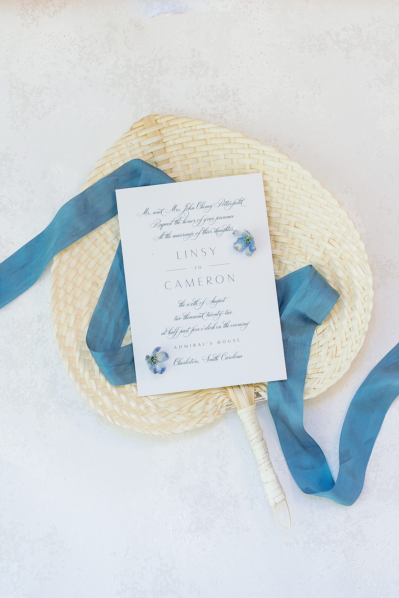 Wedding invitation styled on a sweetgrass fan and blue ribbon | Images by Annie Laura Photography