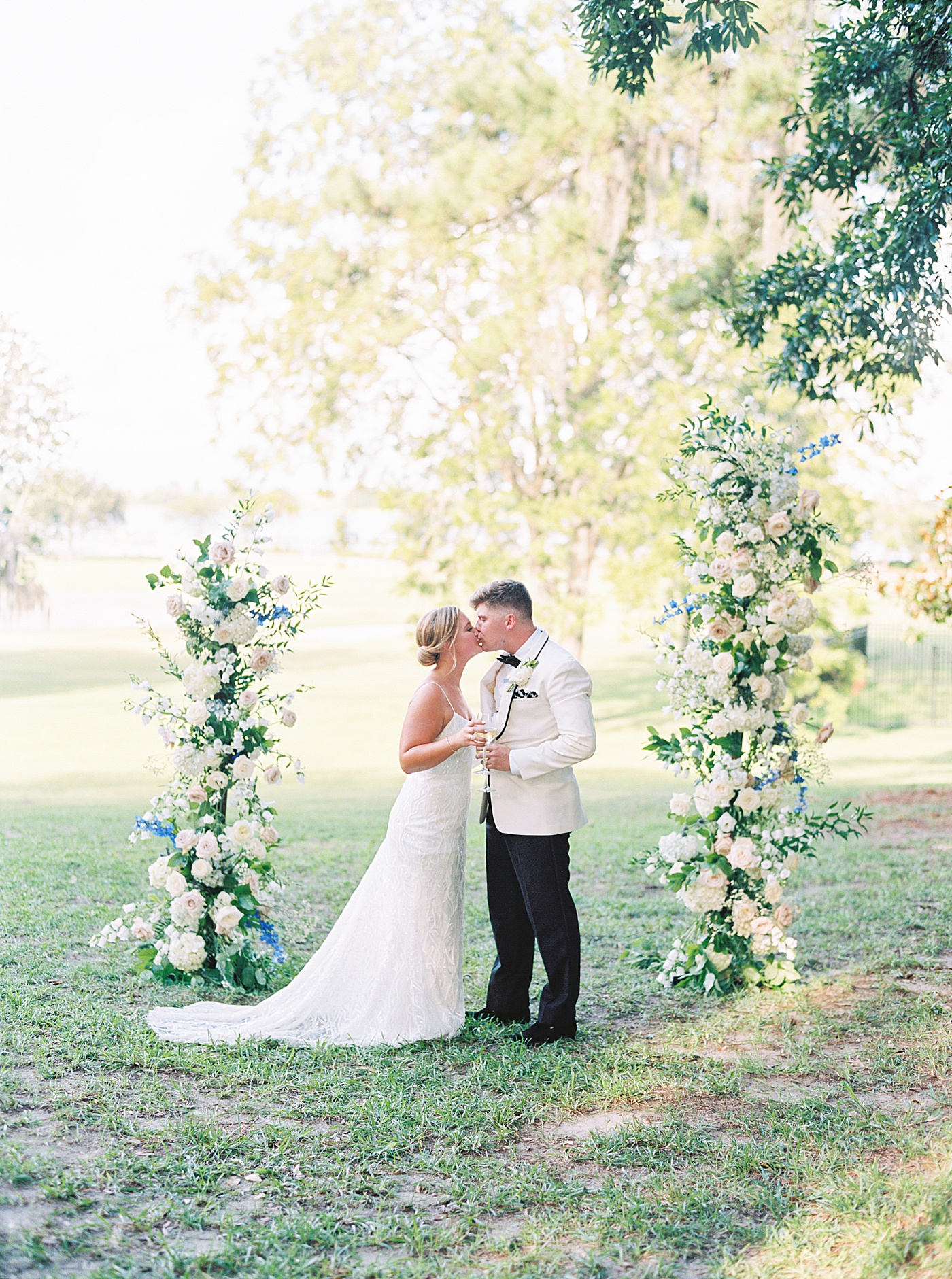 Bride and groom kissing under floral arrangement | Image by Annie Laura Photo