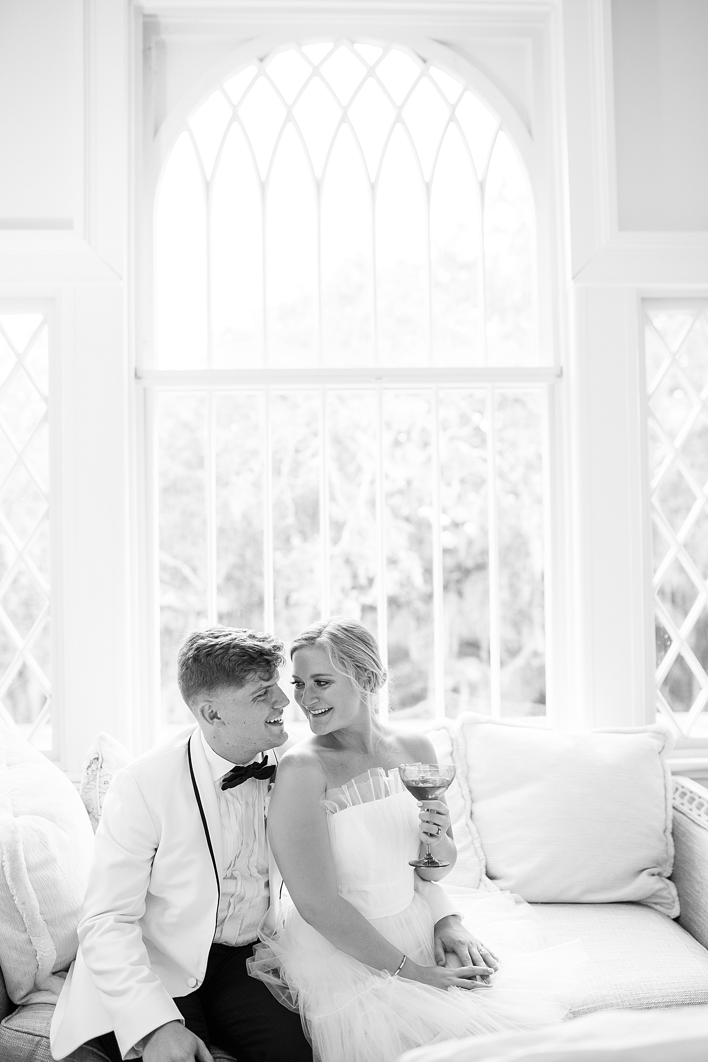 Black and white image of bride and groom sitting on a chaise | Images by Annie Laura Photography