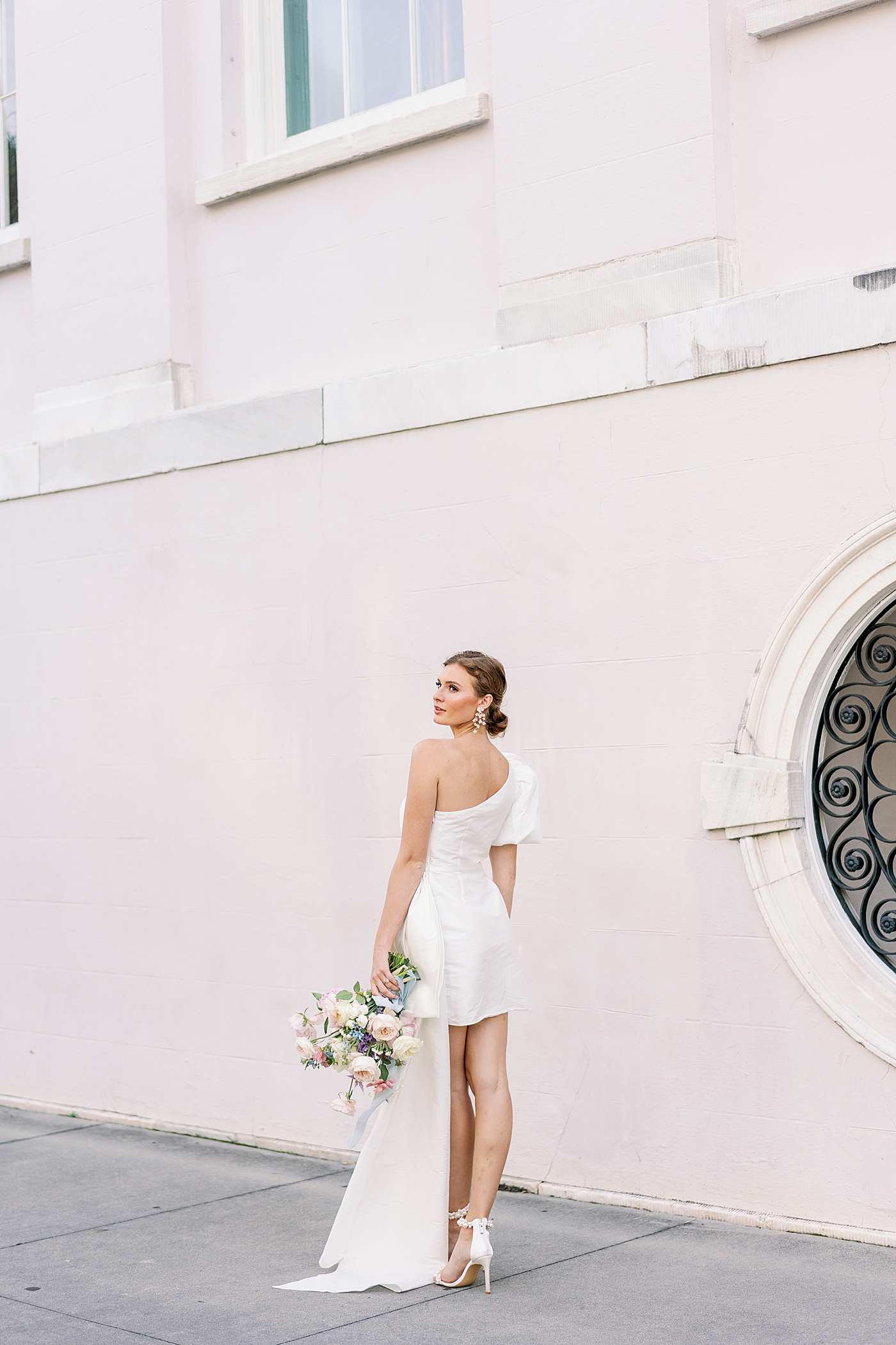 Bride in front of pink wall looking over her shoulder | Images by Annie Laura Photo