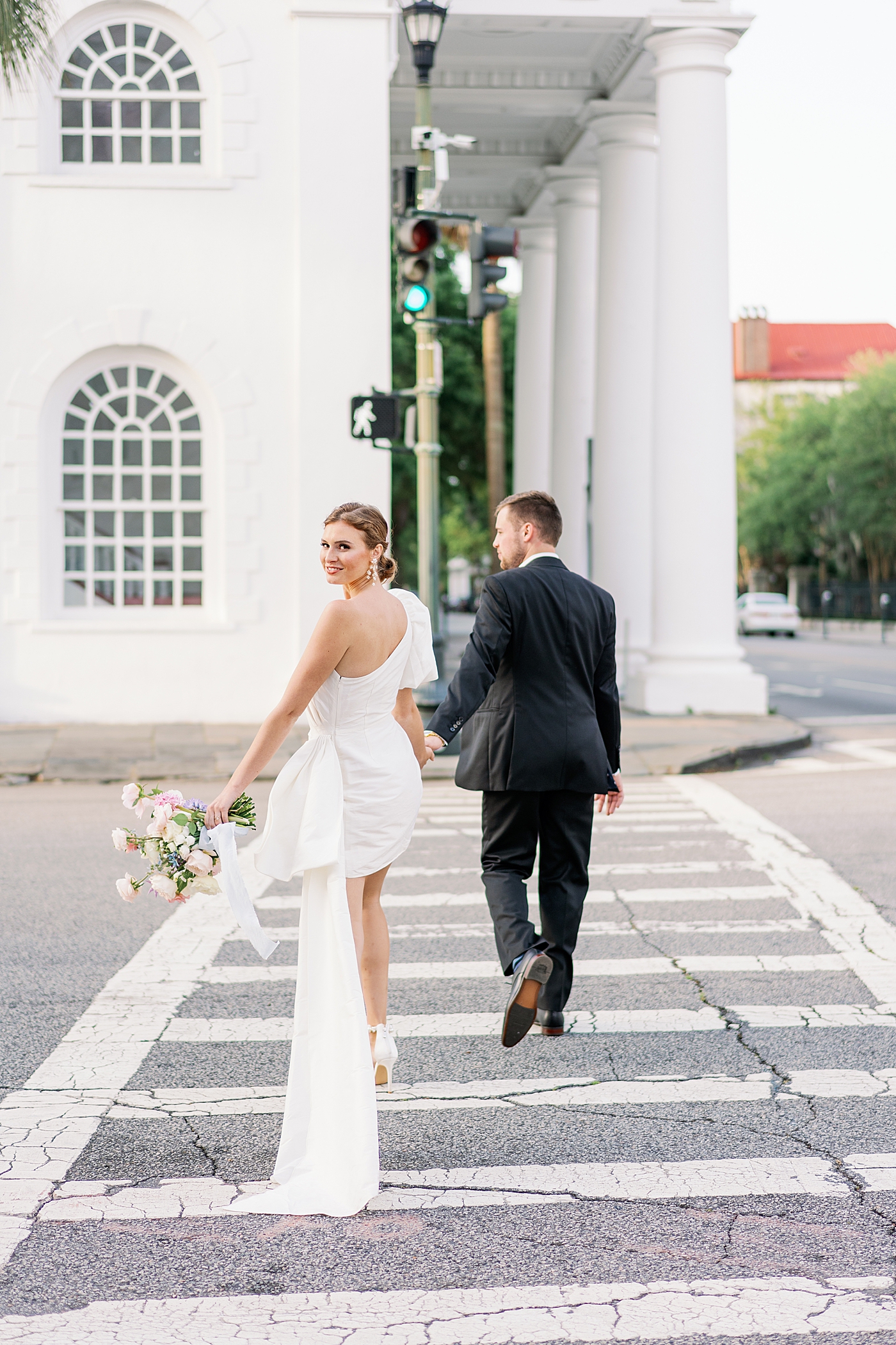 Bride looking over her should while she and groom cross street | Images by Annie Laura Photo