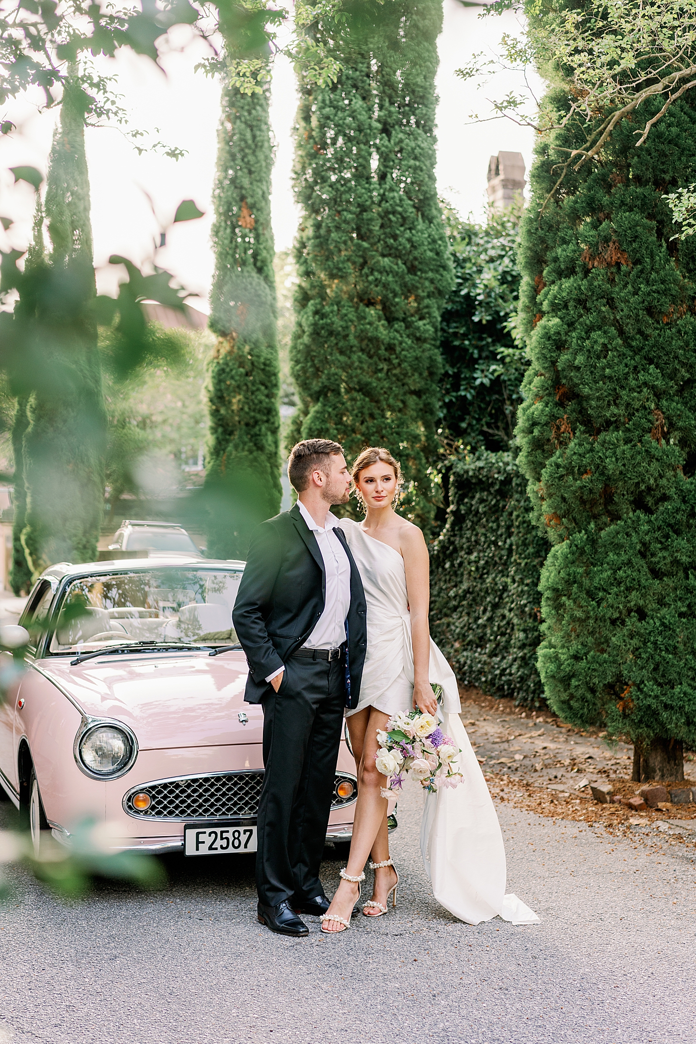 Bride and groom posing near pink car during Elevated City Hall Elopement | Images by Annie Laura Photo