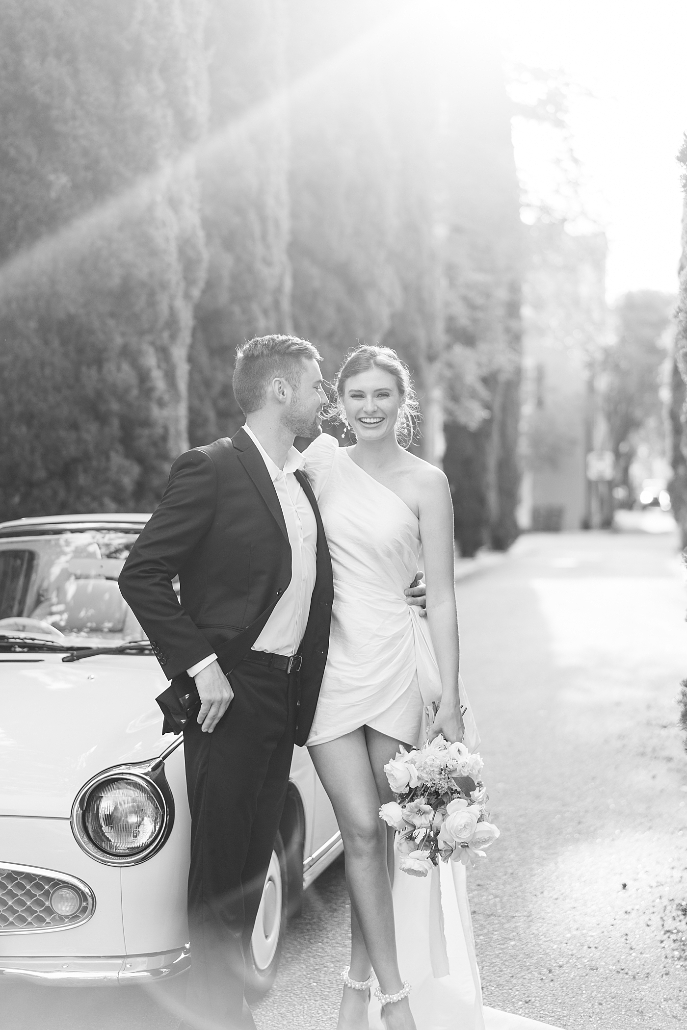 Black and white image of bride and groom near car | Images by Annie Laura Photo