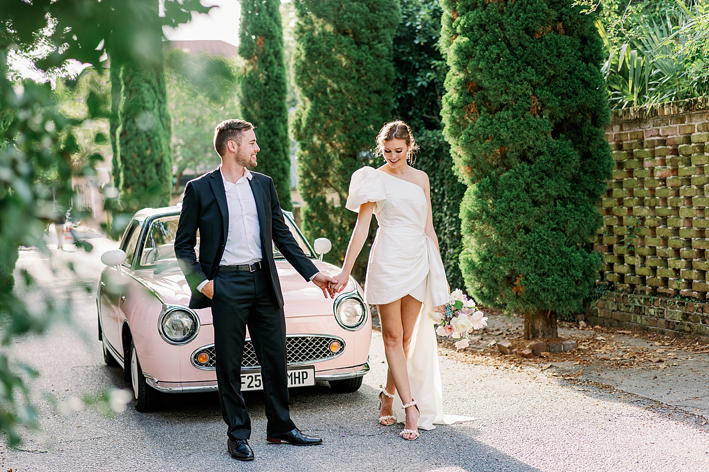 Bride and groom holding hands in front of pink car | Images by Annie Laura Photo
