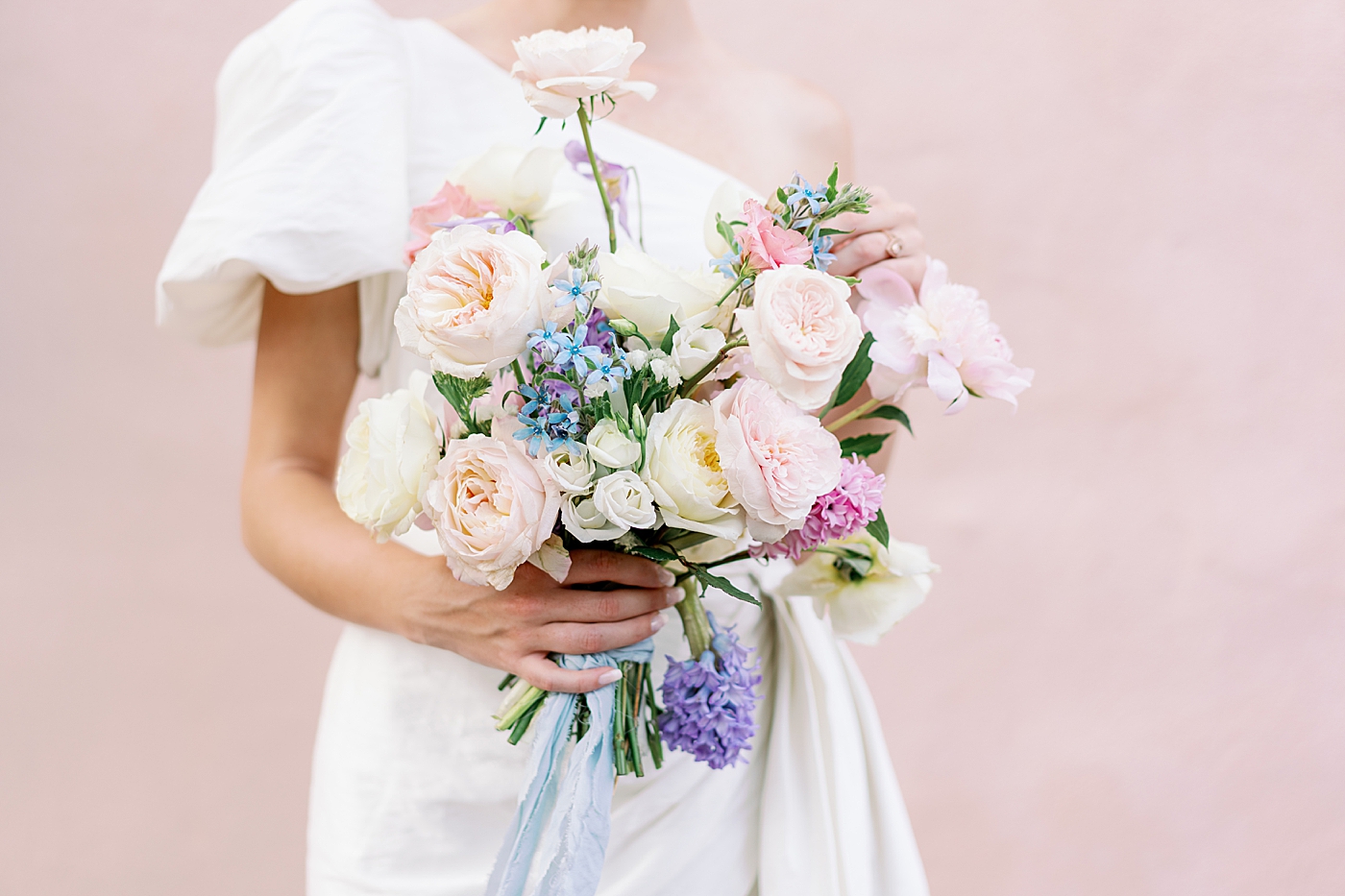Bride near a pink wall admiring her bouquet | Images by Annie Laura Photo
