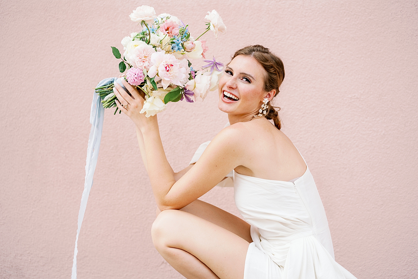 Bride smiling while holding a bouquet with silk ribbon | Images by Annie Laura Photo