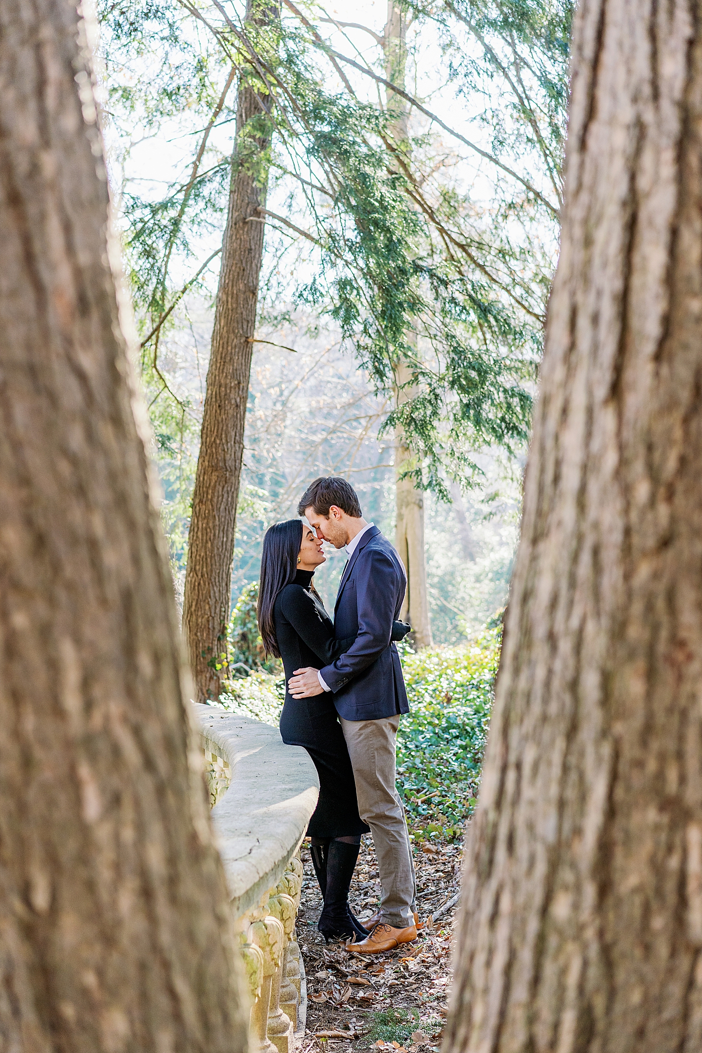 Couple with their foreheads together through two trees | Image by Annie Laura Photo