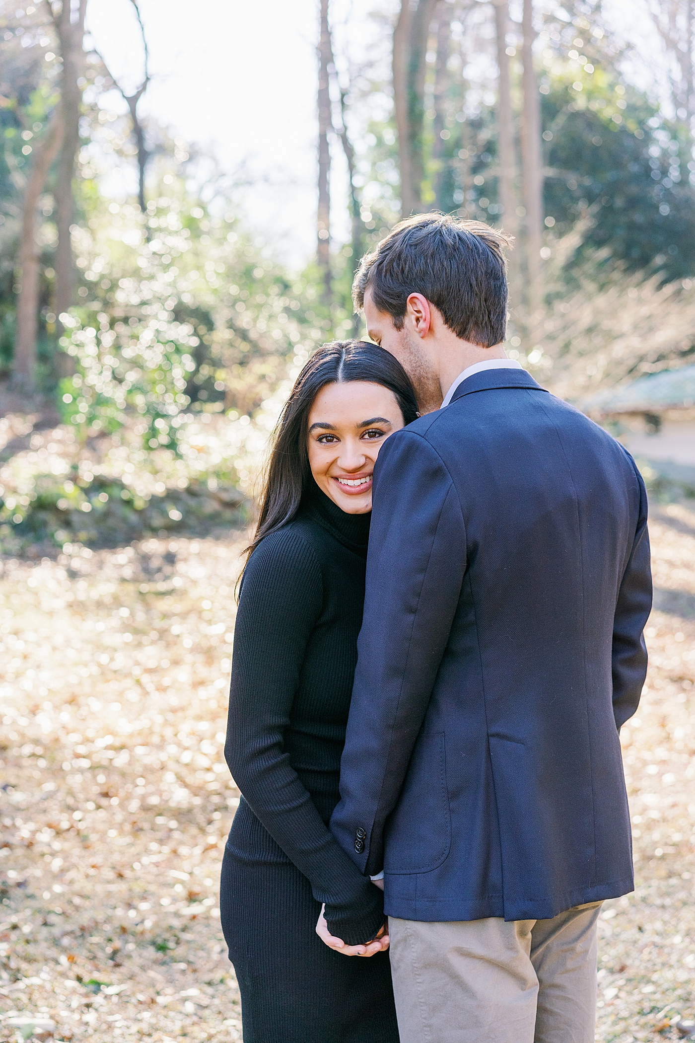 Bride to be in black dress hugging her fiance | Image by Annie Laura Photo