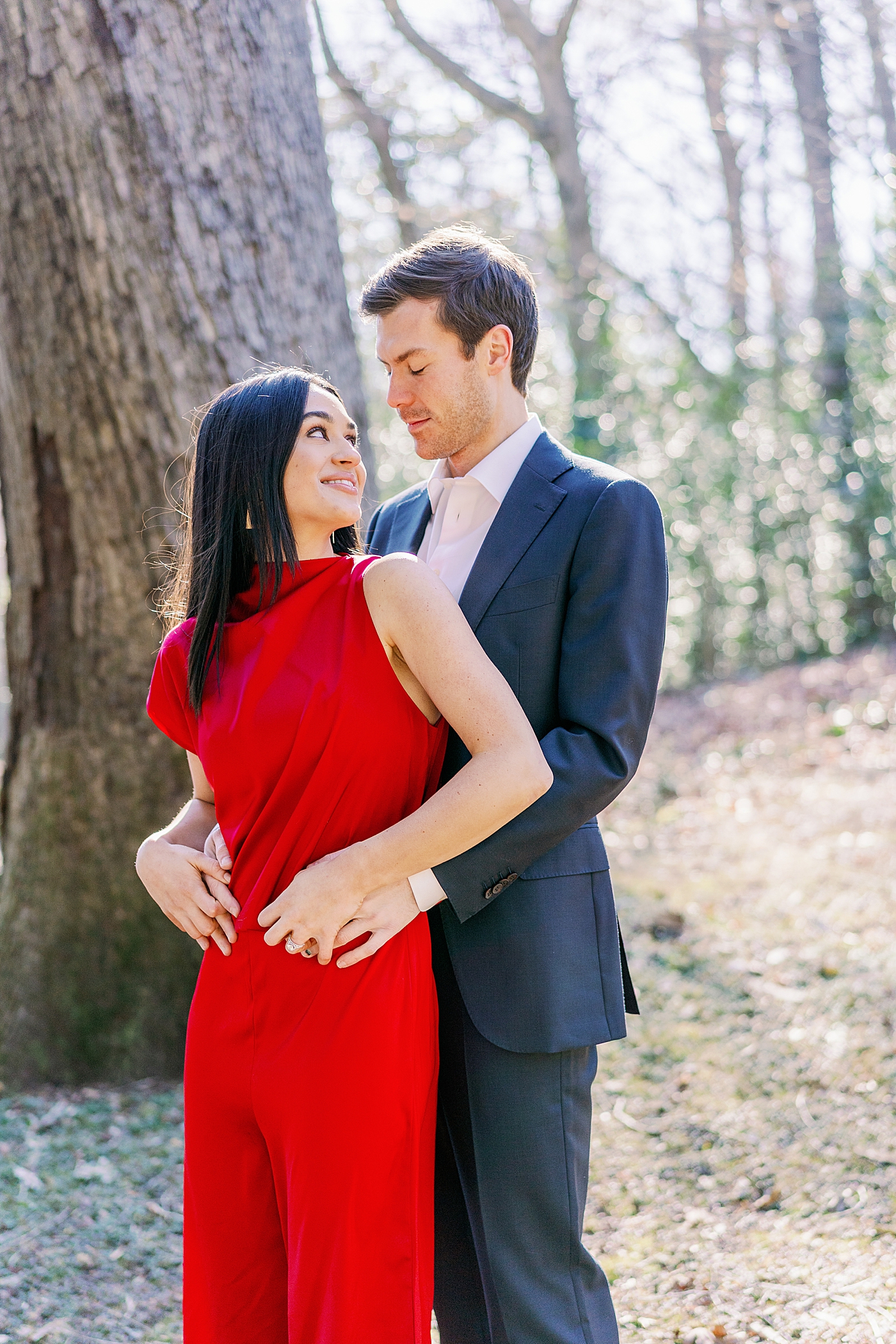 Couple in red and navy embracing during their Atlanta, GA Garden Engagement | Image by Annie Laura Photo