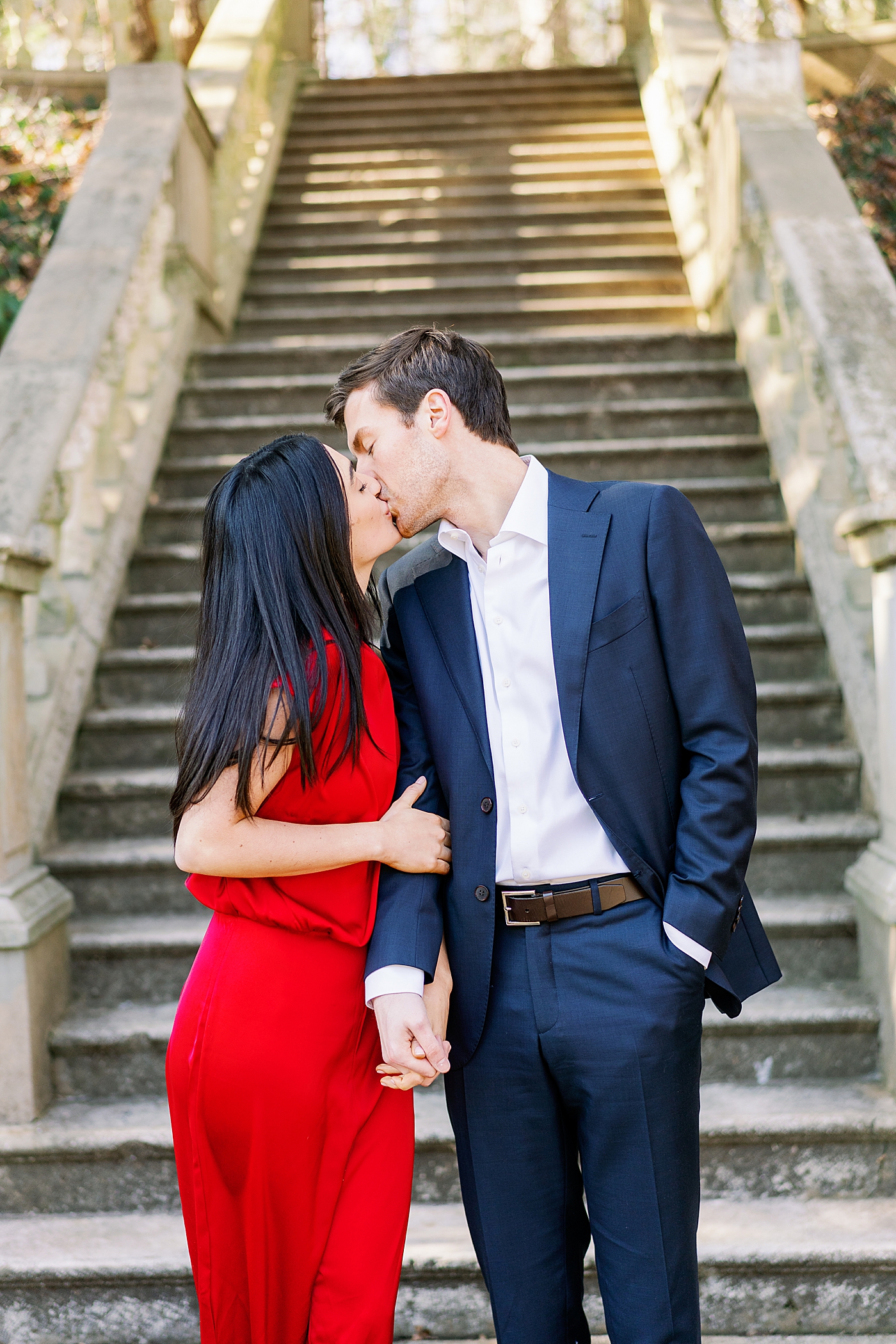 Couple wearing red and blue kissing during their Atlanta, GA Garden Engagement | Image by Annie Laura Photo