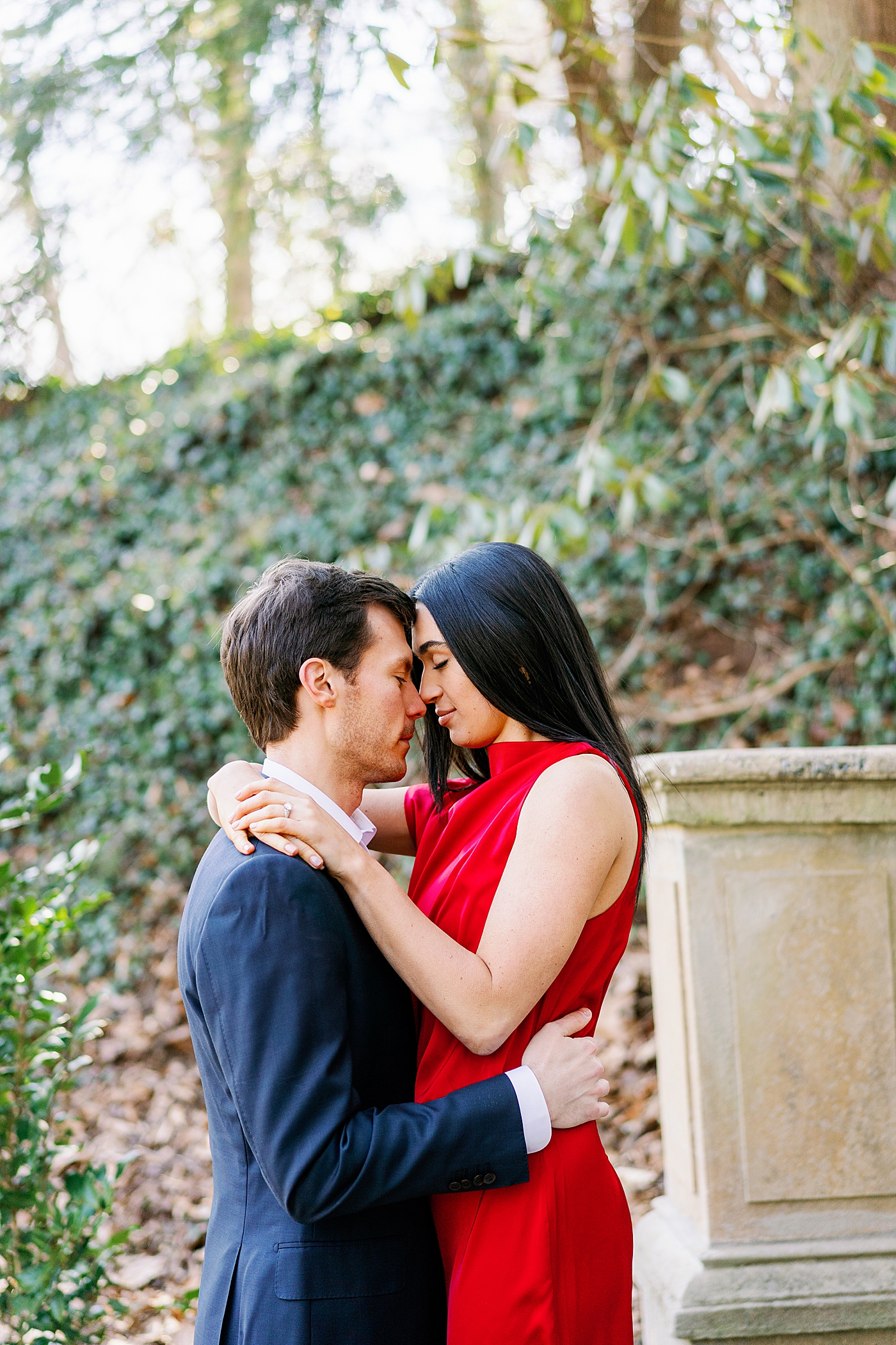 Couple in red and blue with their foreheads together during their Atlanta, GA Garden Engagement | Image by Annie Laura Photo