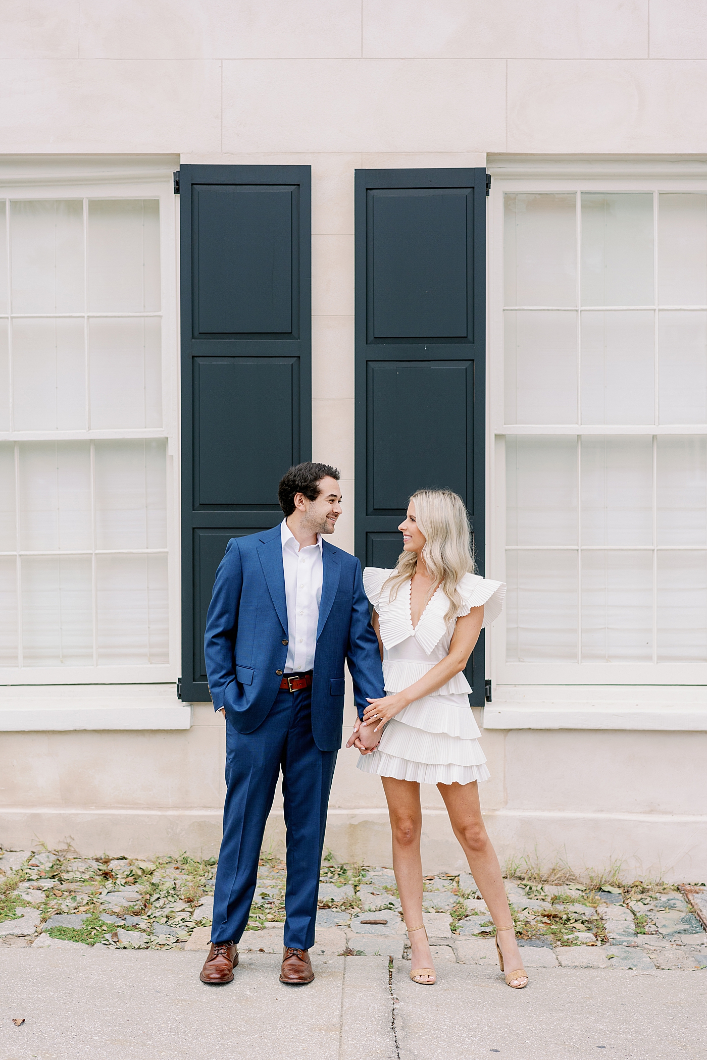 Couple holding hands in front of pink building | Intimate Charleston Engagement Session with Annie Laura Photo