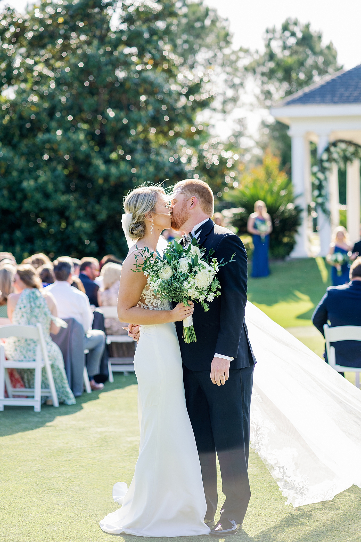 Bride and groom kissing as they walk down the aisle | Image by Annie Laura Photo