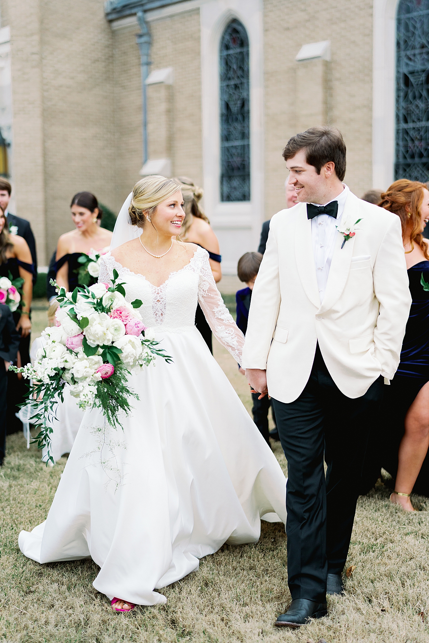 Couple holding hands with their wedding party in the background | Image by Annie Laura Photo