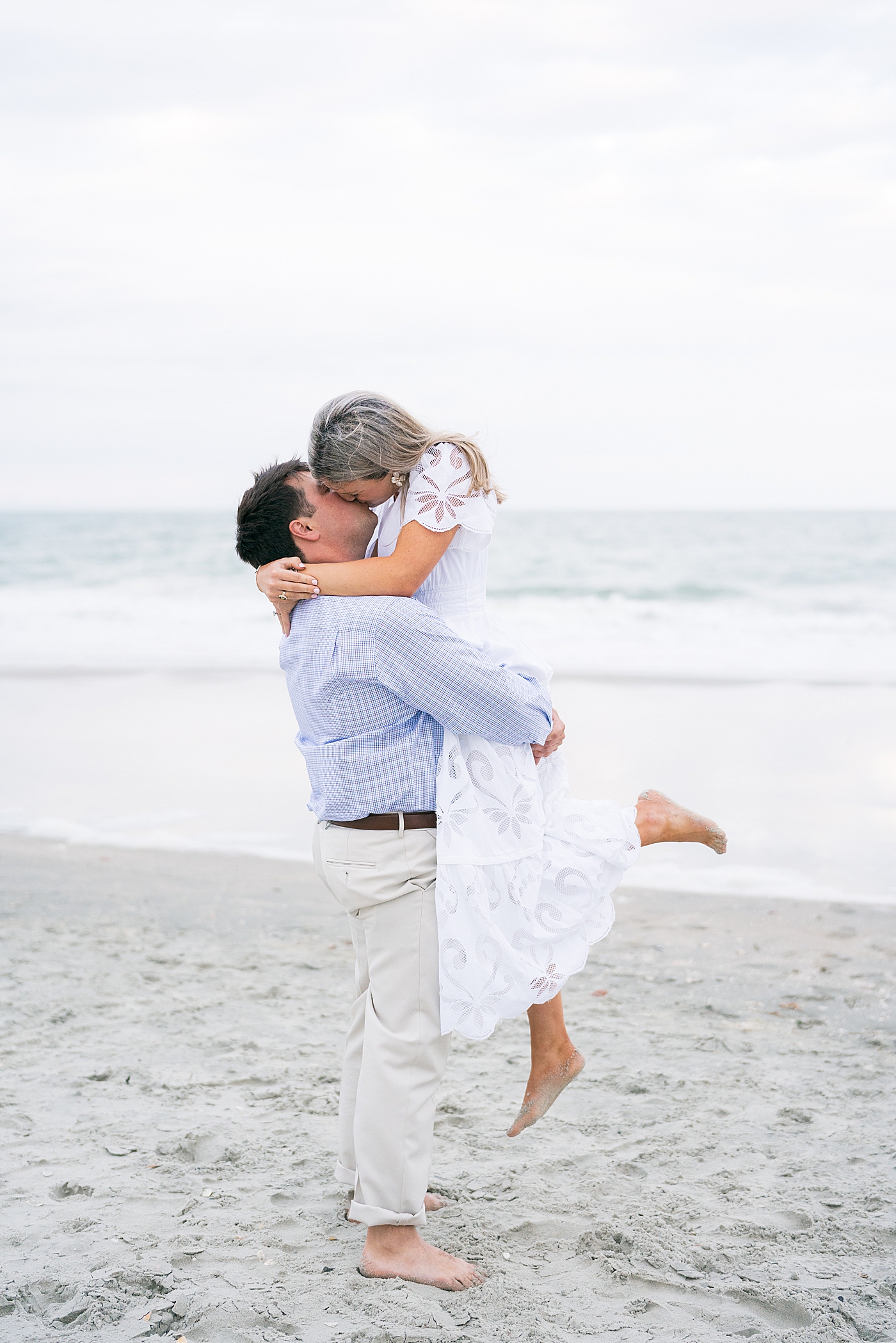 Couple kissing on the beach during their engagement session | Image by Annie Laura Photo