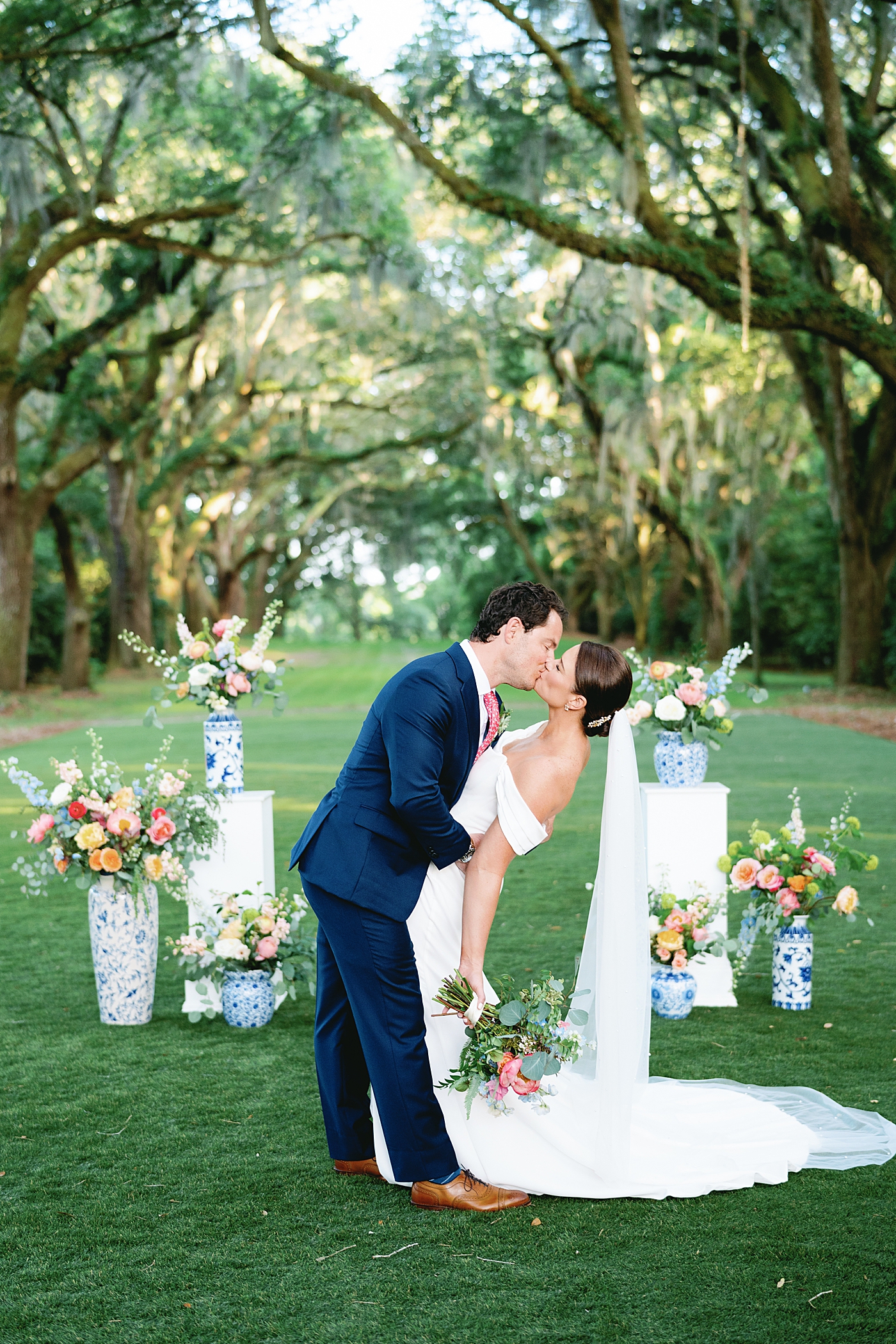 Bride and groom during their first kiss surrounded by colorful florals | Image by Annie Laura Photo