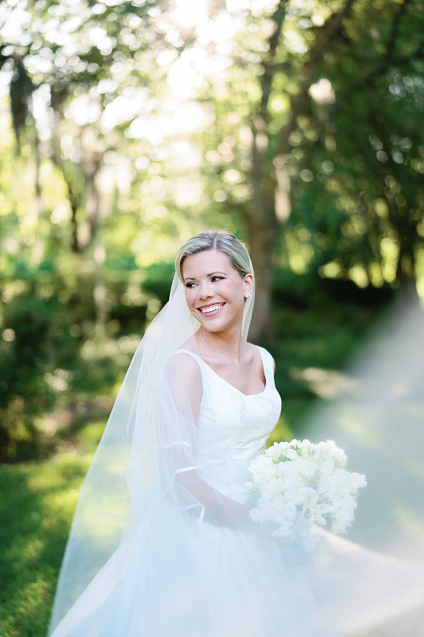 Bride in a veil standing on a porch surrounded by greenery | Image by Annie Laura Photo