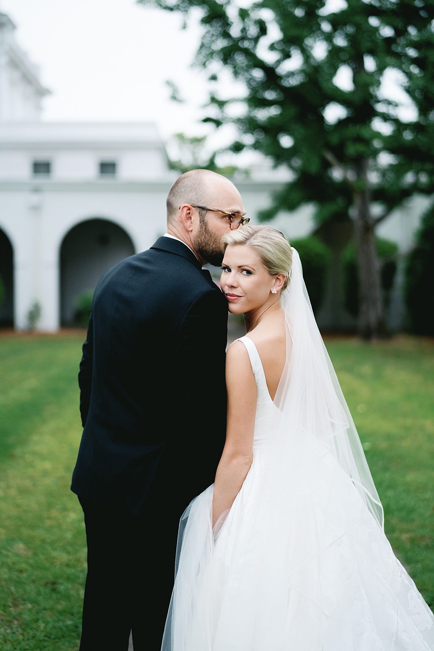 Bride and groom embracing outside of a white church | Image by Annie Laura Photo